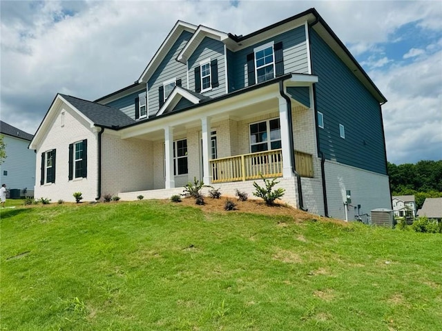 view of front of property featuring central AC, covered porch, and a front yard