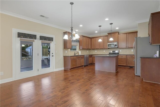 kitchen with a center island, tasteful backsplash, crown molding, decorative light fixtures, and appliances with stainless steel finishes