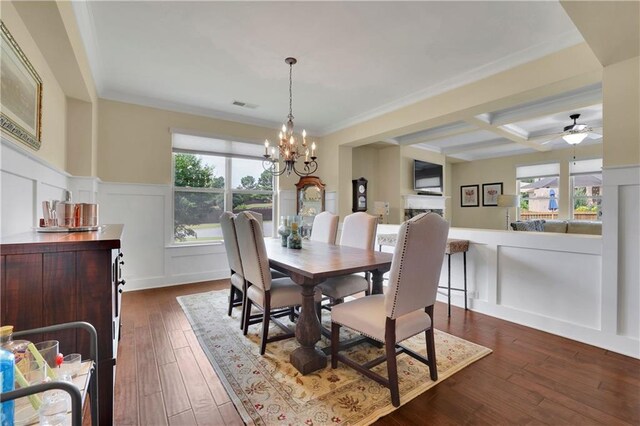 dining area featuring beam ceiling, dark wood-type flooring, coffered ceiling, ceiling fan with notable chandelier, and ornamental molding