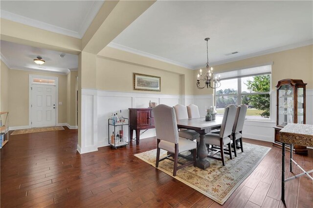 dining area featuring an inviting chandelier, dark hardwood / wood-style floors, and ornamental molding