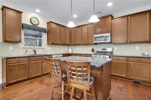 kitchen with gas range, a center island, dark hardwood / wood-style flooring, dark stone countertops, and decorative light fixtures