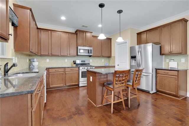 kitchen with a breakfast bar, a center island, dark wood-type flooring, sink, and appliances with stainless steel finishes