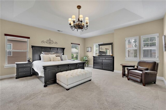 carpeted bedroom with a raised ceiling, multiple windows, and a chandelier