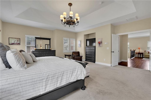 carpeted bedroom featuring a raised ceiling and a notable chandelier