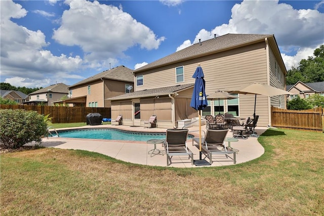 rear view of house featuring a lawn, a patio, and a fenced in pool