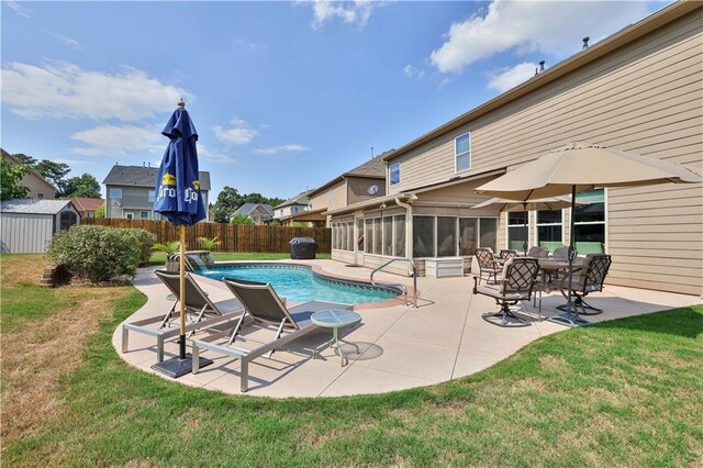 view of pool with a sunroom, pool water feature, a patio area, and a lawn