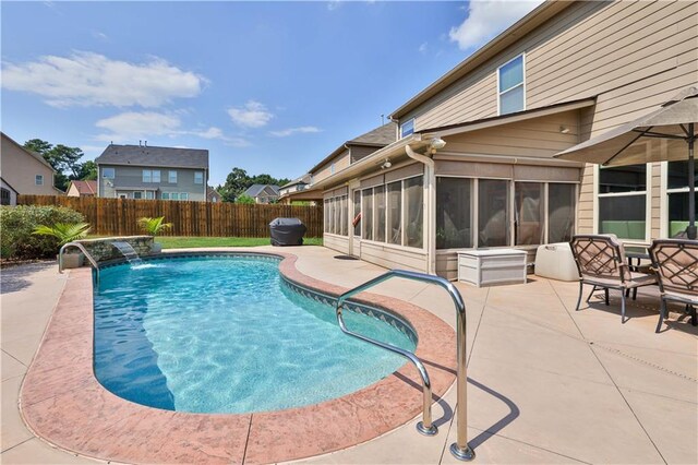 view of pool with pool water feature, a patio, and a sunroom