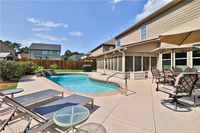 view of swimming pool featuring a sunroom, pool water feature, and a patio