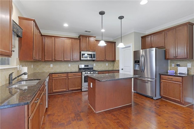 kitchen featuring appliances with stainless steel finishes, backsplash, sink, pendant lighting, and a kitchen island