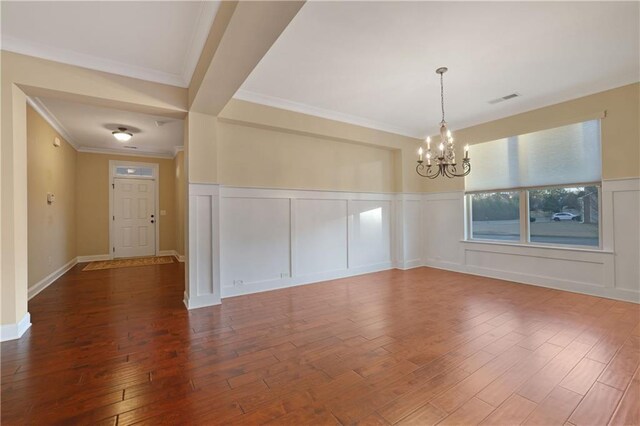 interior space featuring wood-type flooring, ornamental molding, and an inviting chandelier