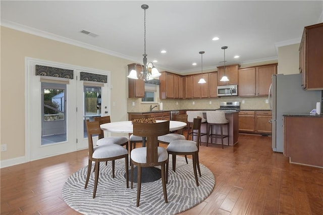 dining area featuring dark hardwood / wood-style flooring, an inviting chandelier, and ornamental molding