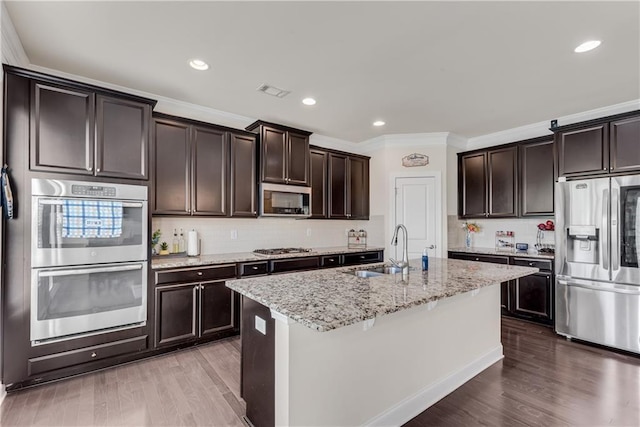 3950 Grandview Manor Dr, Cumming, GA 30028 - kitchen featuring stainless steel appliances, a sink, dark brown cabinetry, crown molding, and light stone countertops