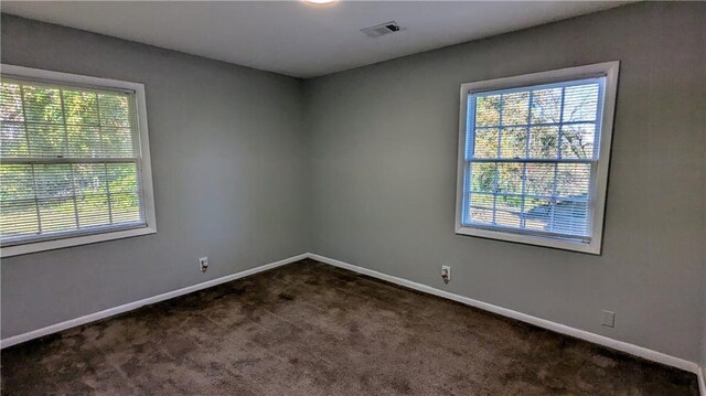 unfurnished room featuring dark colored carpet