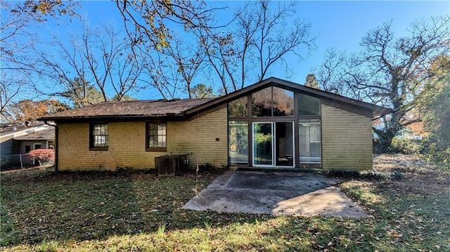 rear view of house featuring a patio, central AC, and a lawn