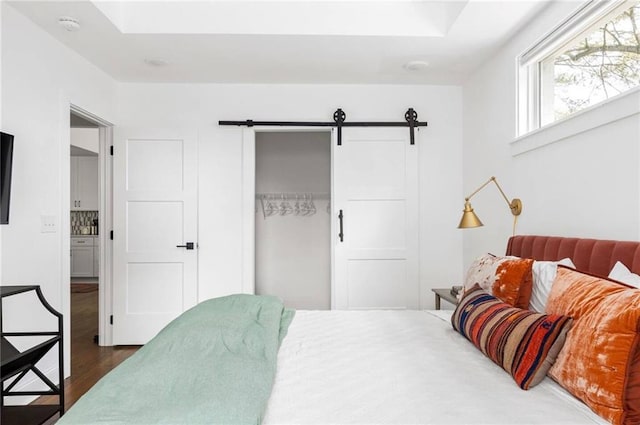 bedroom with dark wood-type flooring, a barn door, and a closet