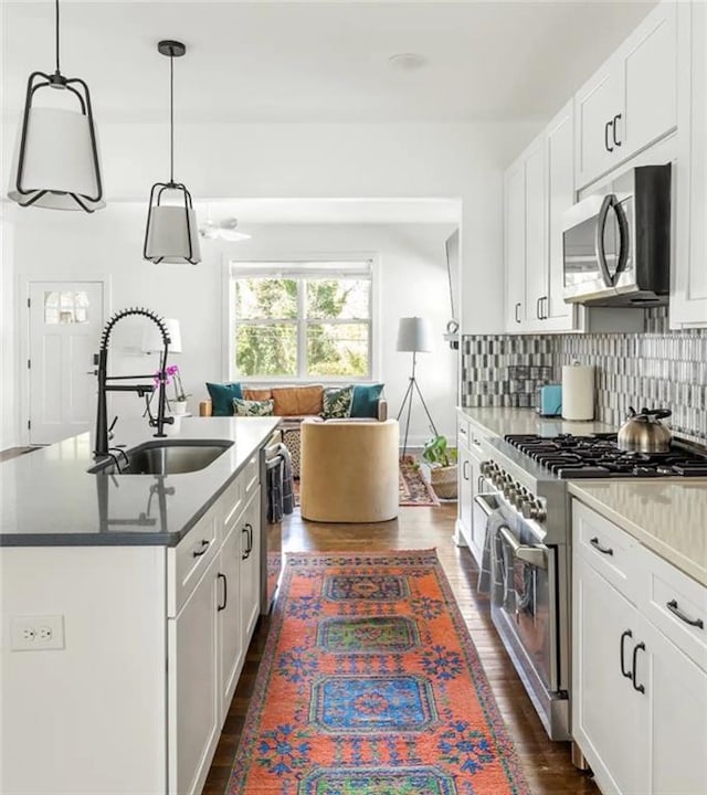 kitchen with sink, white cabinetry, stainless steel appliances, pendant lighting, and dark hardwood / wood-style floors