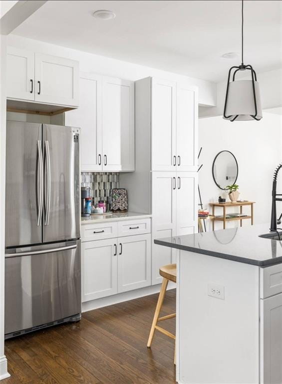 kitchen featuring white cabinets, hanging light fixtures, and stainless steel refrigerator