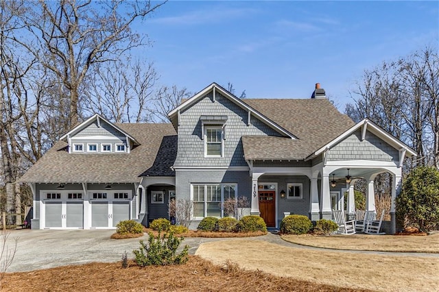 craftsman-style home with ceiling fan, covered porch, roof with shingles, a chimney, and concrete driveway