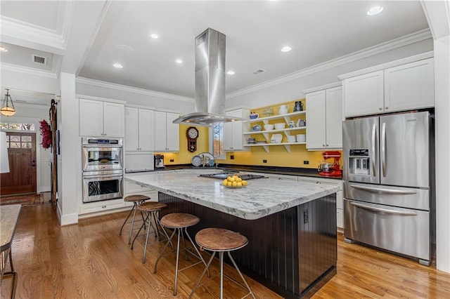 kitchen featuring visible vents, a kitchen island, light wood-style floors, island range hood, and appliances with stainless steel finishes