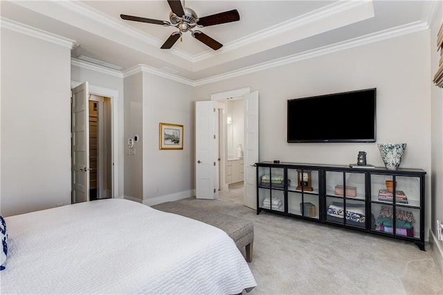 carpeted bedroom featuring ceiling fan, a raised ceiling, baseboards, ornamental molding, and ensuite bathroom