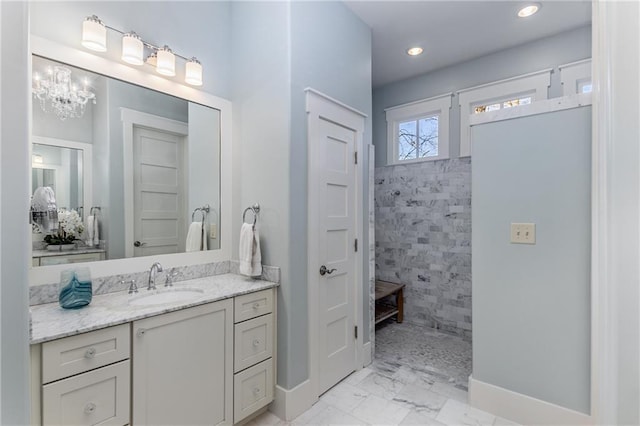 full bathroom featuring vanity, an inviting chandelier, marble finish floor, baseboards, and walk in shower