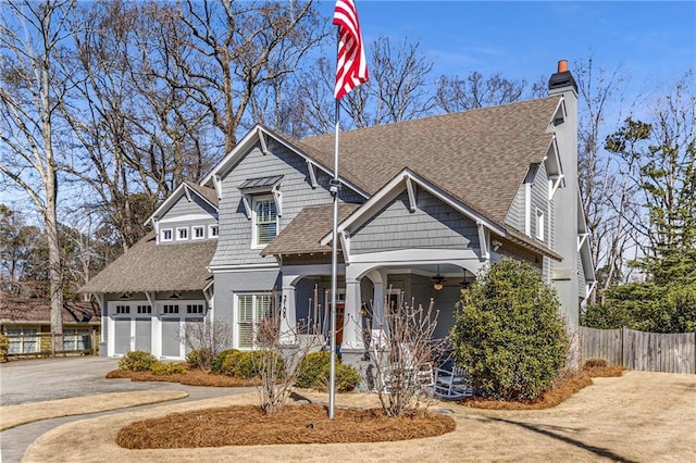 craftsman-style home with covered porch, fence, a shingled roof, and driveway