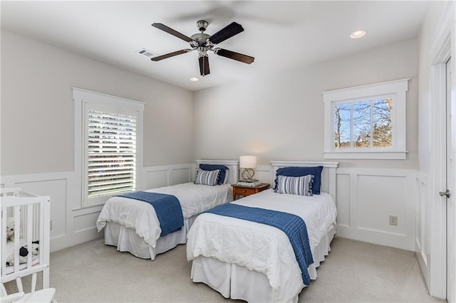 carpeted bedroom featuring visible vents, a decorative wall, and a wainscoted wall