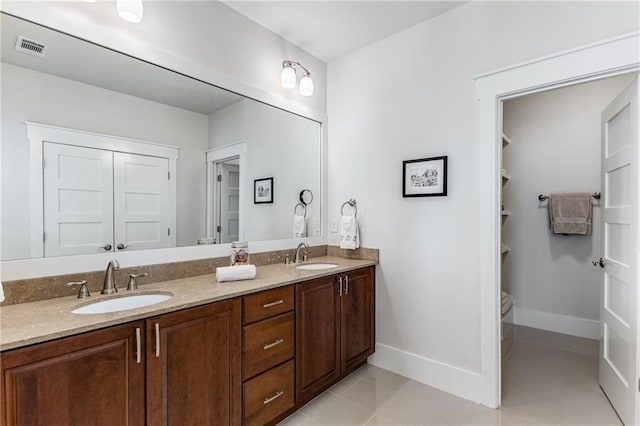 bathroom featuring a sink, baseboards, double vanity, and visible vents