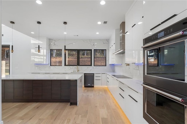 kitchen with wall chimney exhaust hood, white cabinetry, black electric cooktop, double oven, and pendant lighting