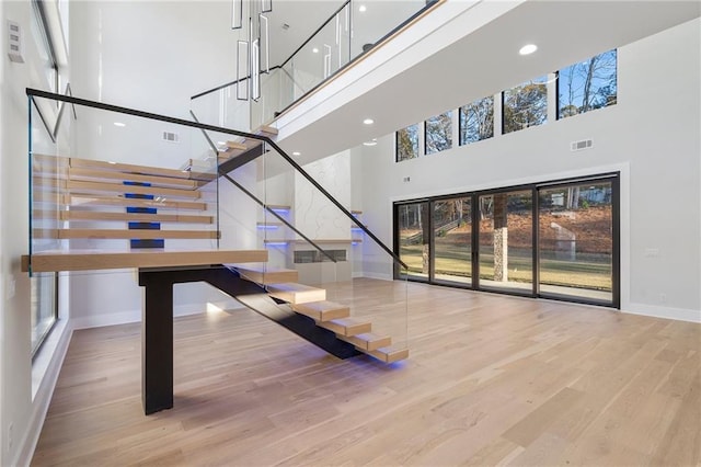 staircase featuring a towering ceiling and hardwood / wood-style floors