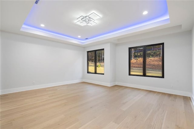 spare room with light hardwood / wood-style floors and a tray ceiling