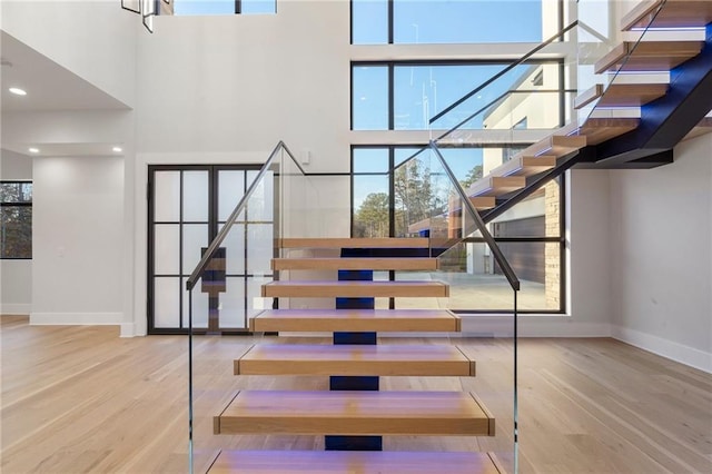 stairs featuring hardwood / wood-style flooring and a high ceiling