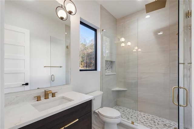 bathroom featuring vanity, toilet, and a shower with shower door