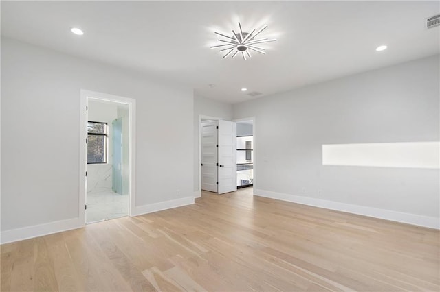 unfurnished bedroom with ensuite bathroom, a walk in closet, and light hardwood / wood-style flooring