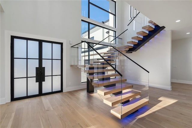 stairway with a towering ceiling and wood-type flooring