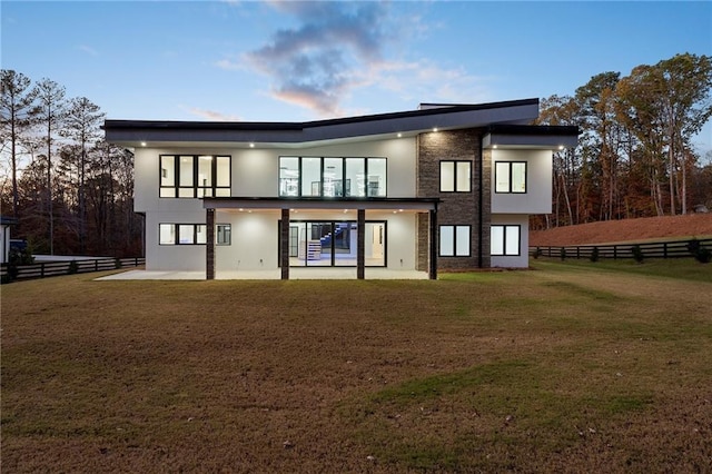 back house at dusk featuring a yard and a patio