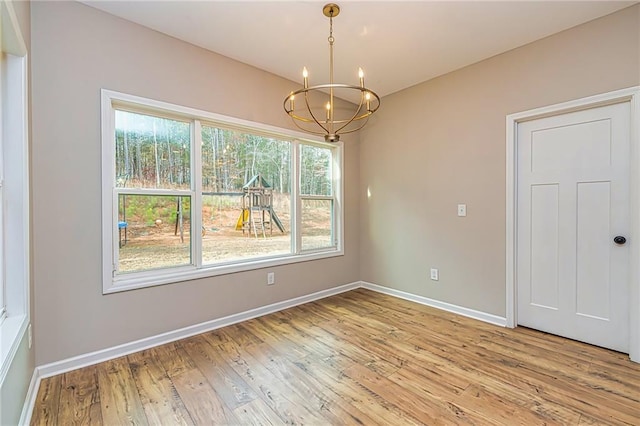 unfurnished dining area featuring a notable chandelier and wood-type flooring