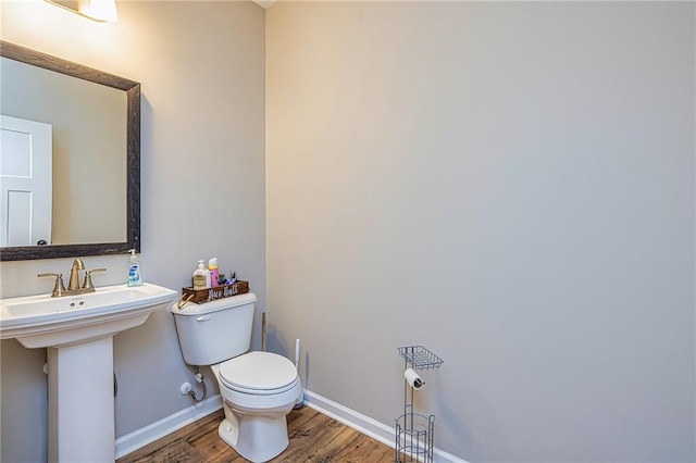 bathroom featuring toilet, wood-type flooring, and sink