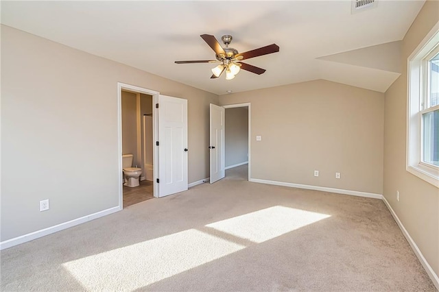 unfurnished bedroom with ensuite bath, ceiling fan, light colored carpet, and vaulted ceiling