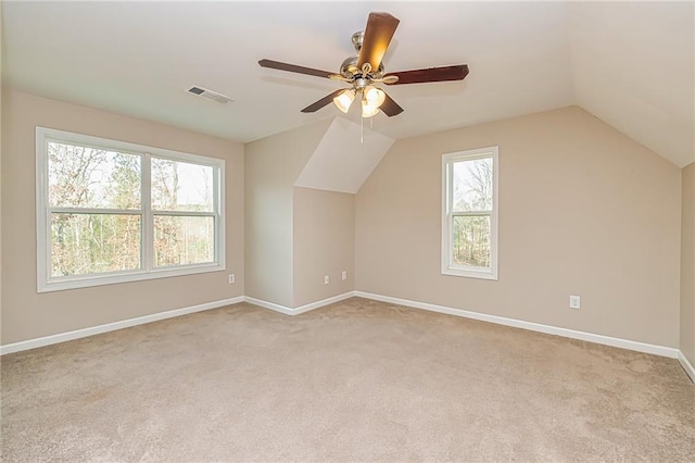 additional living space with a wealth of natural light, ceiling fan, light colored carpet, and vaulted ceiling