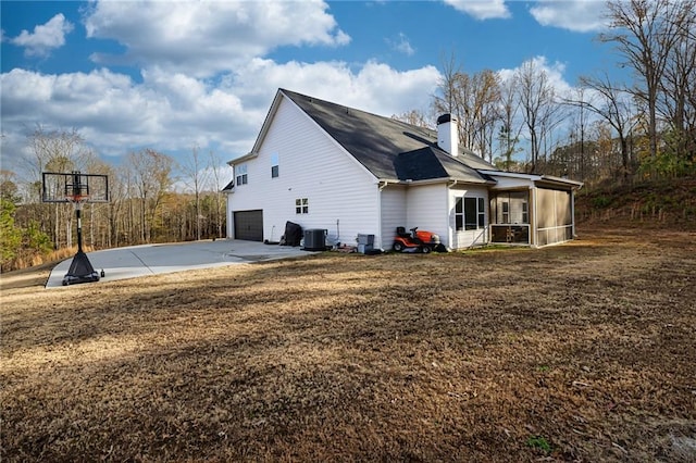 view of property exterior with a yard, a garage, central AC unit, and a sunroom