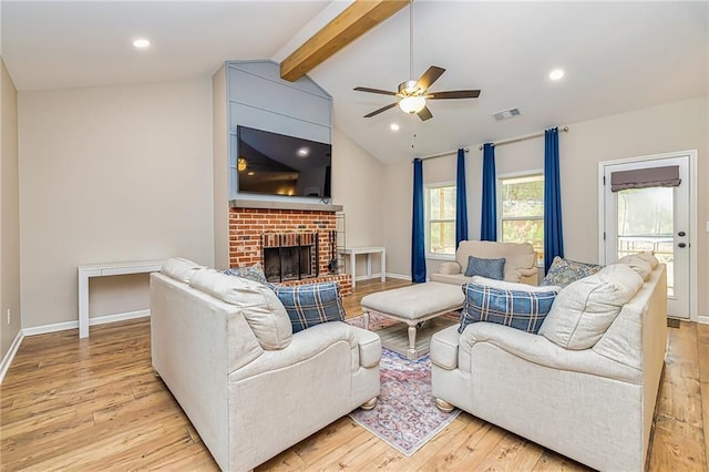 living room with vaulted ceiling with beams, ceiling fan, light wood-type flooring, and a fireplace