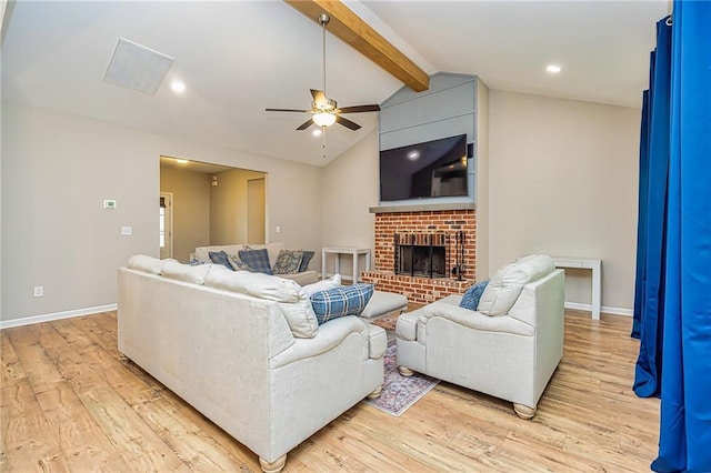 living room featuring lofted ceiling with beams, light hardwood / wood-style floors, ceiling fan, and a brick fireplace