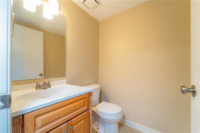 bathroom featuring vanity, toilet, a textured ceiling, and baseboards