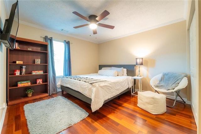 bedroom featuring wood finished floors, crown molding, ceiling fan, and a textured ceiling