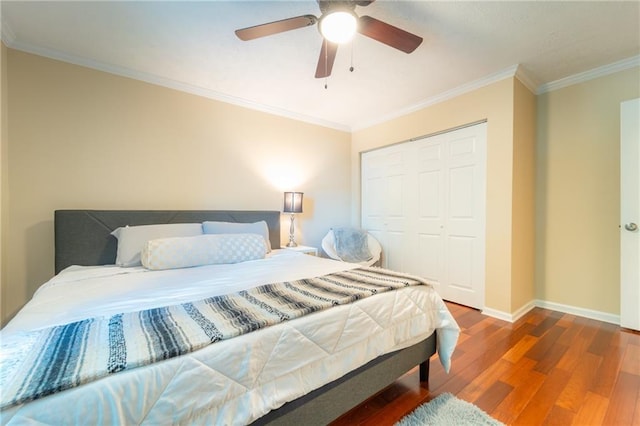 bedroom featuring wood finished floors, baseboards, a closet, ornamental molding, and ceiling fan