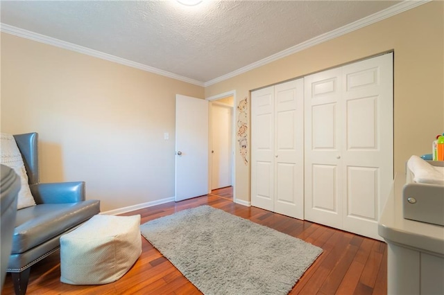 living area featuring ornamental molding, wood-type flooring, a textured ceiling, and baseboards