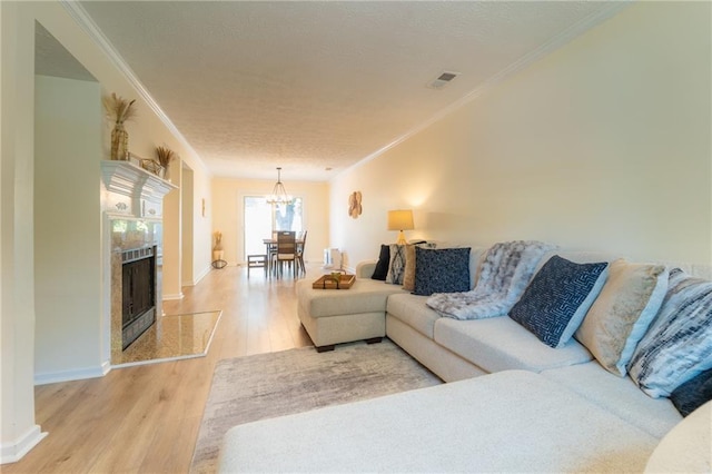 living area with wood finished floors, a chandelier, a tiled fireplace, ornamental molding, and baseboards
