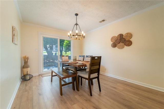 dining room featuring a chandelier, light wood-type flooring, crown molding, baseboards, and a textured ceiling
