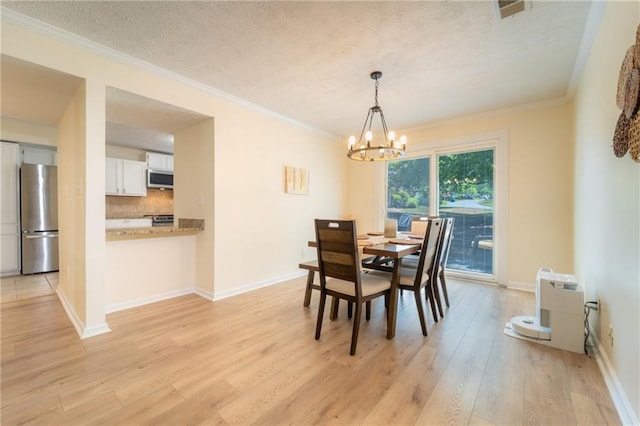 dining room with light wood finished floors, a chandelier, a textured ceiling, ornamental molding, and baseboards
